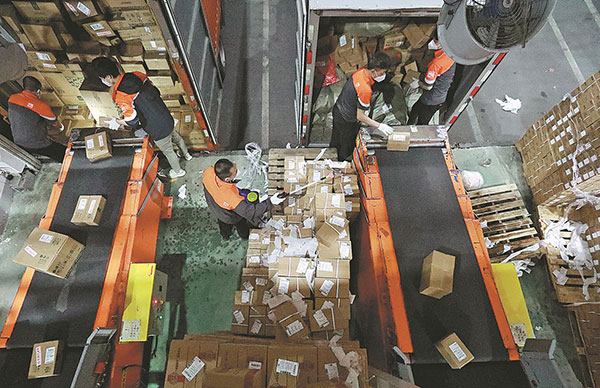 周三晚上，工人们在上海青浦区申通快递的配送中心对从卡车上下来的包裹进行分类。中心已恢复服务，人员实行闭环管理，并采取严格的消毒措施。朱兴新/中国日报